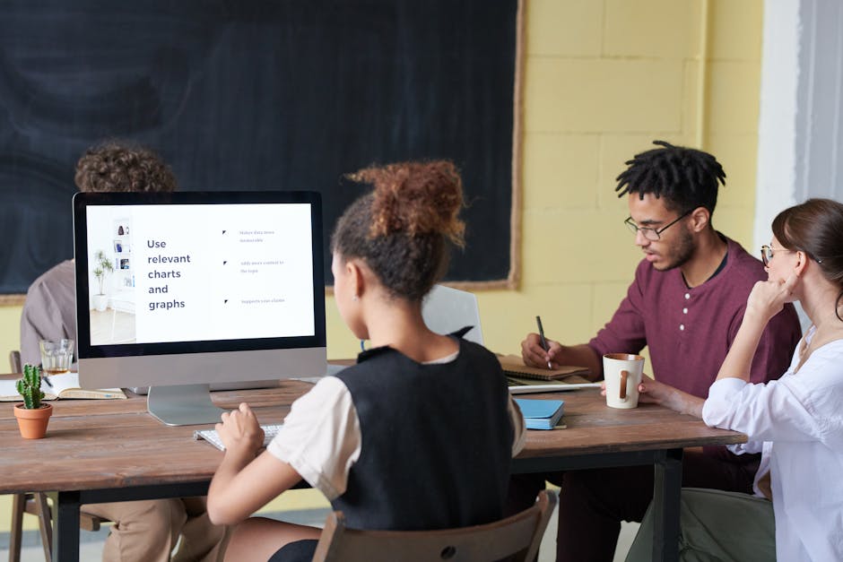 A diverse group of adults collaborating in a modern office space with a computer display.